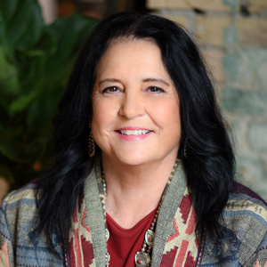 Linda Bane Frizzell smiling while wearing a traditional Native American sweater.