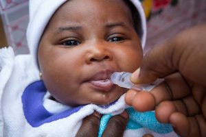 A baby swallows a dose of oral vaccine.