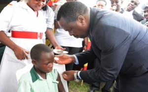 A child sitting in a chair is given an HPV vaccination by a doctor.