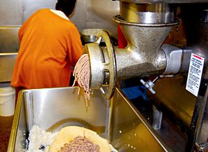 Pork being ground through a commercial grinder.