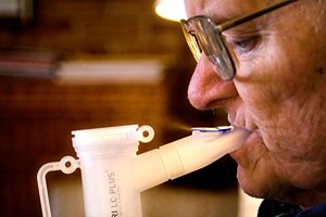 An elderly man breathes through a nebulizer