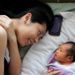 A mother and her baby together in bed.