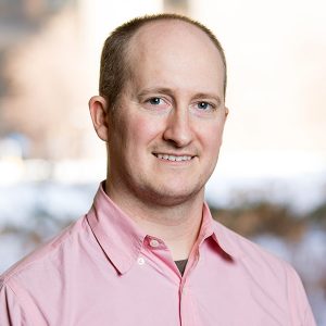 Eric Lock smiling in front of a window.