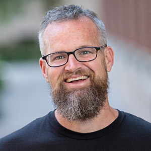 Jude Mikal in a black t-shirt smiling.