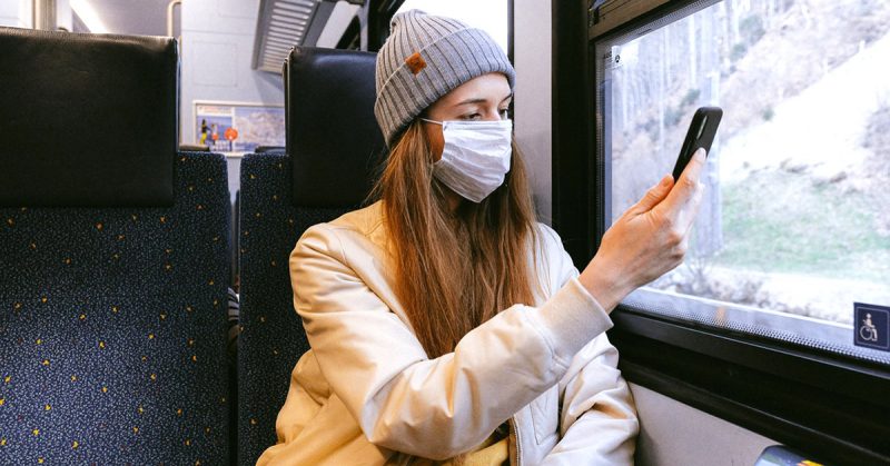 Woman wearing a surgical mask using her phone.
