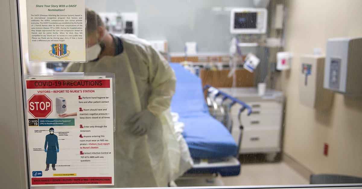 A health care provider working inside a hospital room.