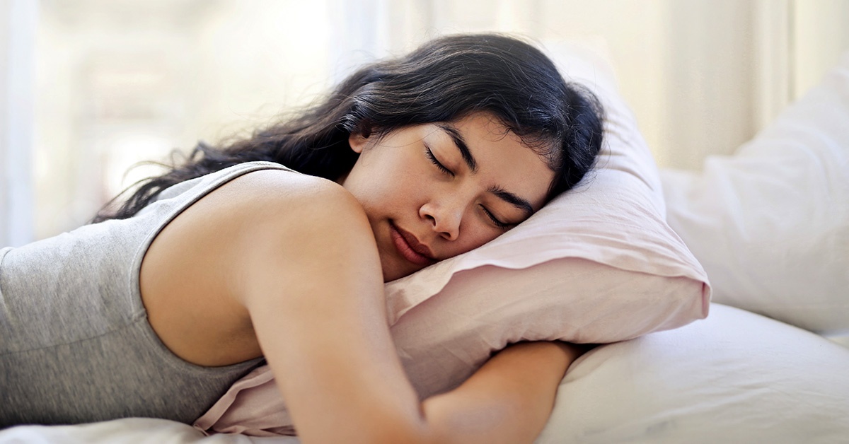 A teenage girl sleeps in her bed.