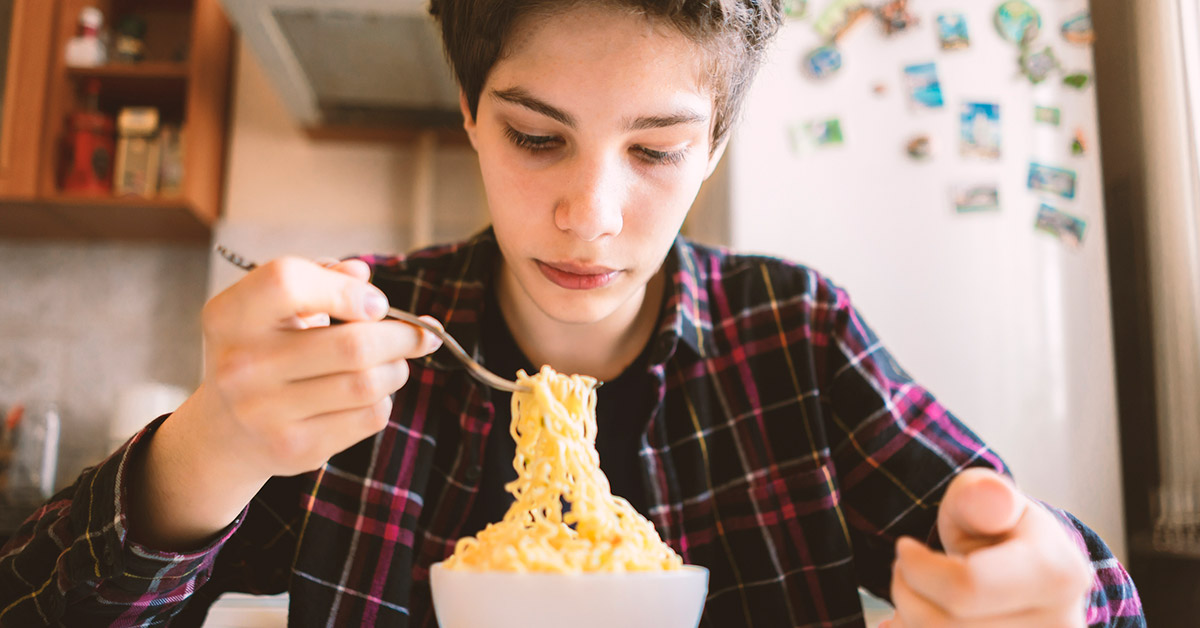 A boy eating a bowl of ramen.