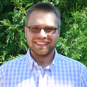 Austin Rau smiling in front of a tree.