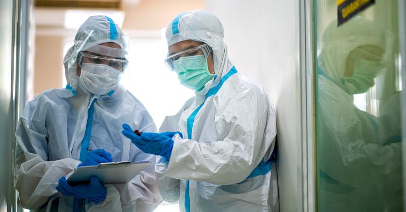 Two providers in PPE stand in a doorway.