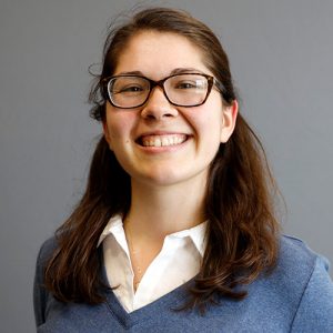 Delaine Anderson smiling and wearing a white shirt and blue sweater.