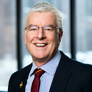 Simon Rosser in a suit and tie standing in front of a window.