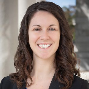 Caitlin Carroll smiling while wearing black dress clothes.