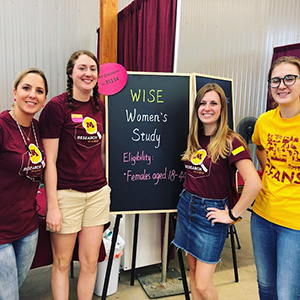 Four female student researcher inside the Driven to Discover Research Facility.