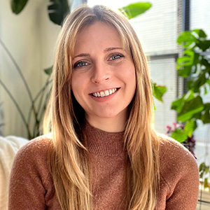 Ashley Oglesby wearing a brown sweater and smiling.