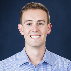 Riley Shearer smiling in a blue and white dress shirt.