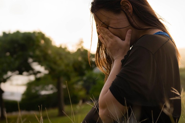 hp-small-feature-intimate-violence woman in field looking very sad