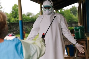 person in full bio-hazard suit getting sprayed with something