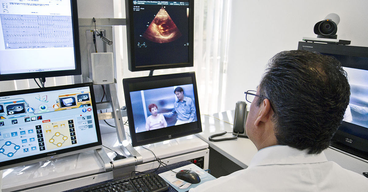 A health care provider uses a computer to consult with a patient.