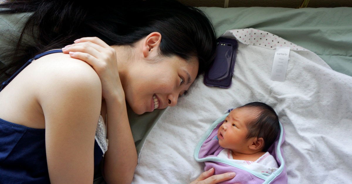 A mother and her baby together in bed.