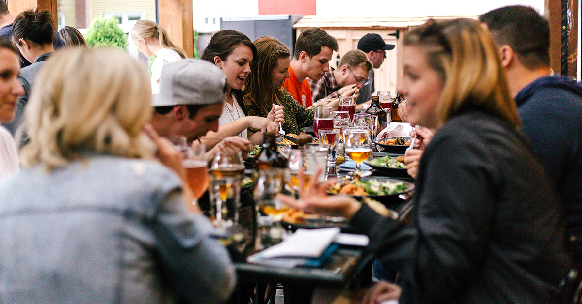 A group of young adults eating at a table.