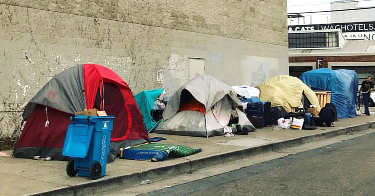 A row of tents standing alongside a building.