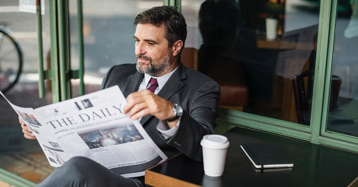 A man in a business suit reading a newspaper