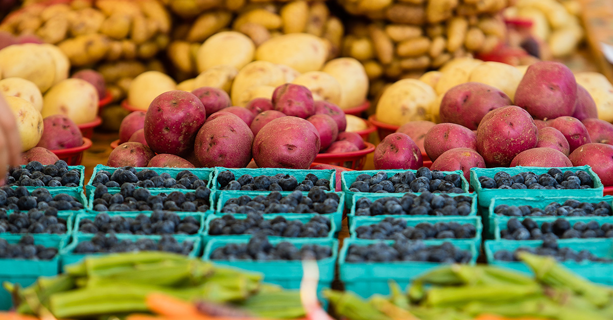 Trays of vegetables on display at a farmers market.