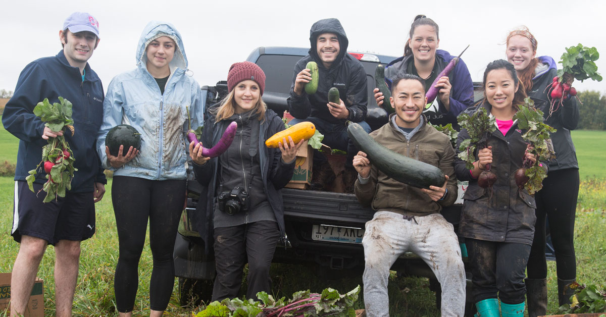 group of people in field displaying their vegetables