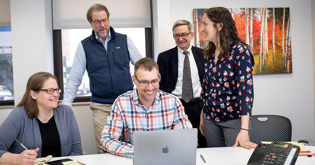 Five people standing around a table.