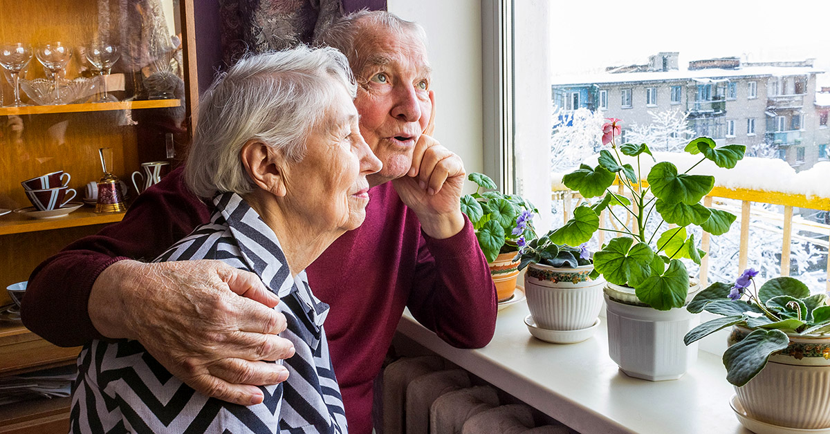 A senior couple at home sitting near window together