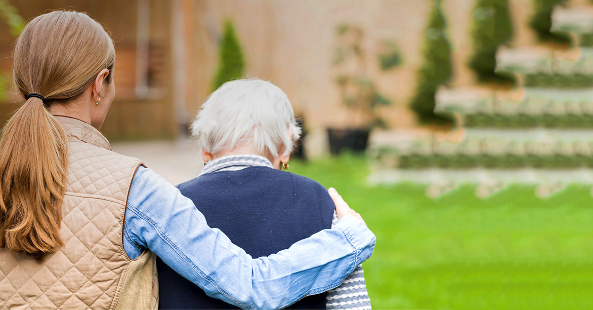 A young woman hugs an aging person.