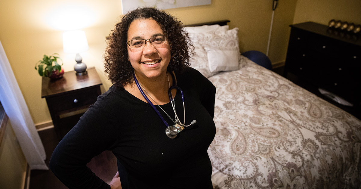 A midwife smiling inside a bedroom of a birthing center.