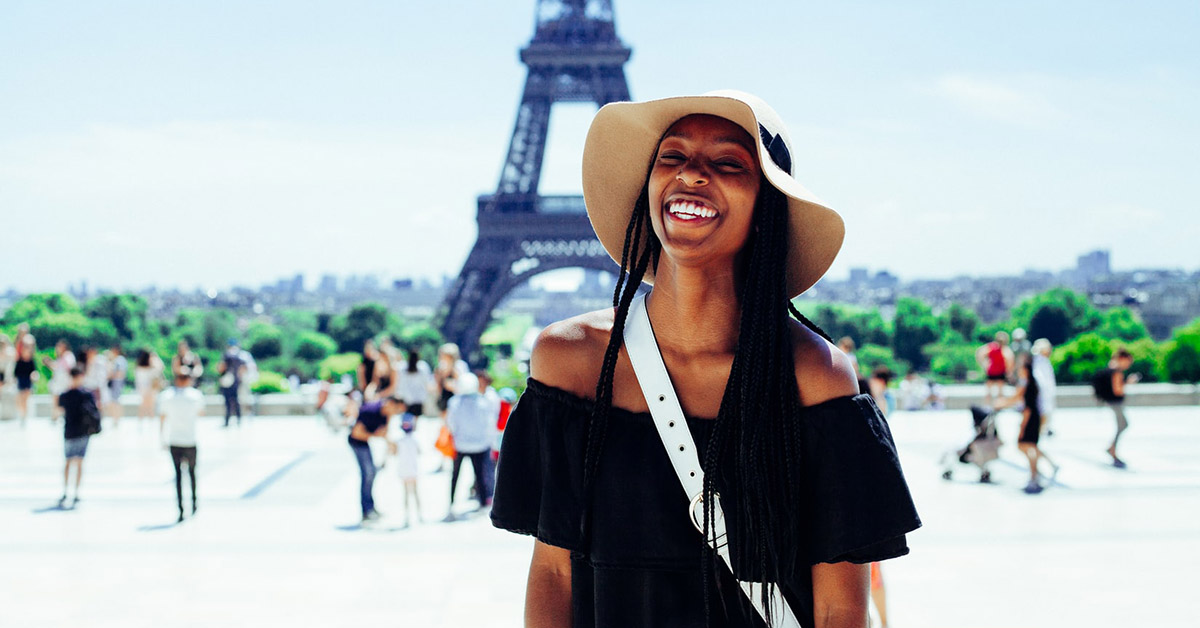 A young woman posing in front of the Eiffel Tower in Paris.