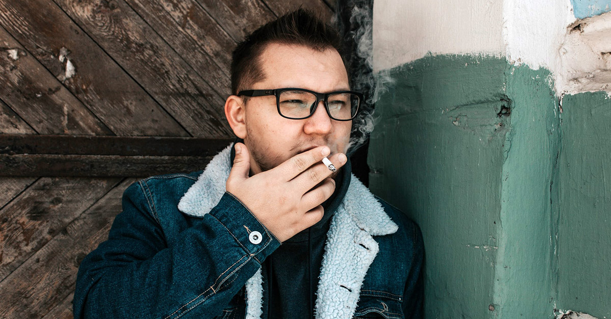 A man smoking a cigarette outside of a building.