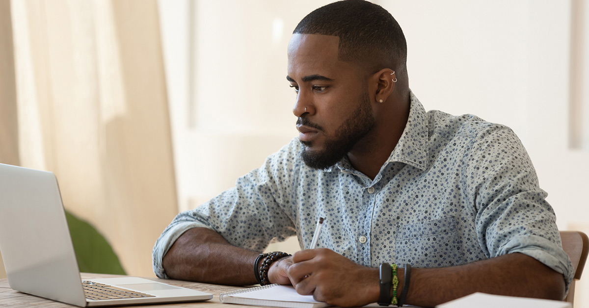 A Black male student studying at his computer.