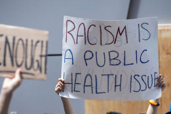 protester holding up sign that says racism is a public health issue