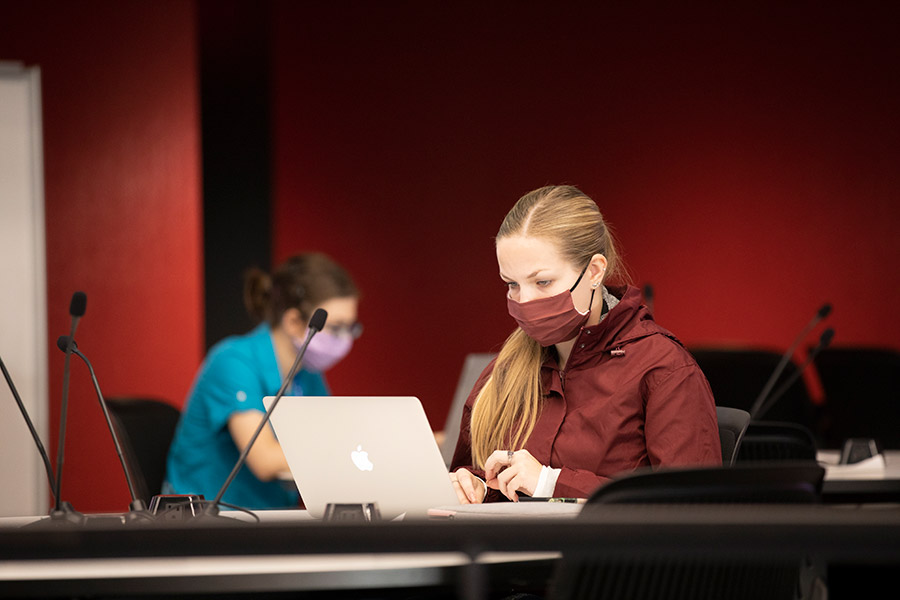 student looking at computer in a mask