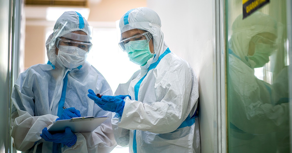 Two providers in PPE stand in a doorway.