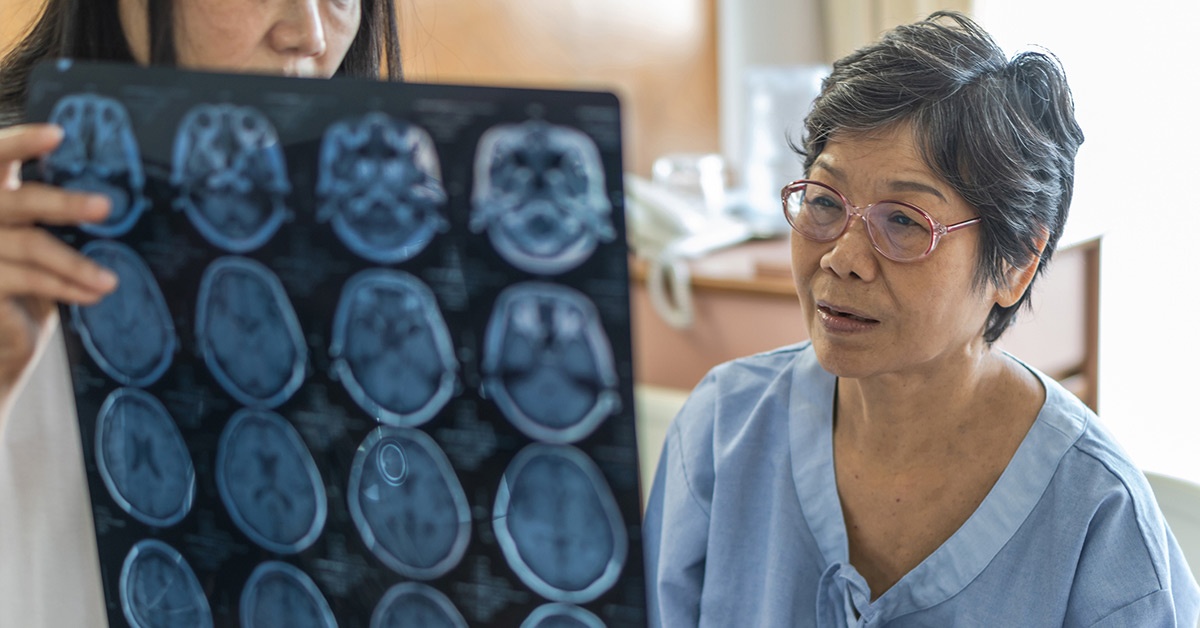 An Asian female patient looks at brain scan images with a doctor.