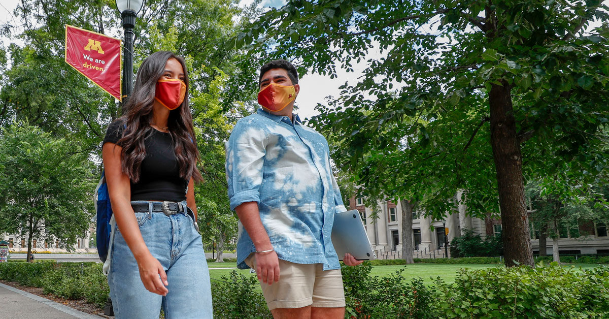 Two students walking on campus with masks