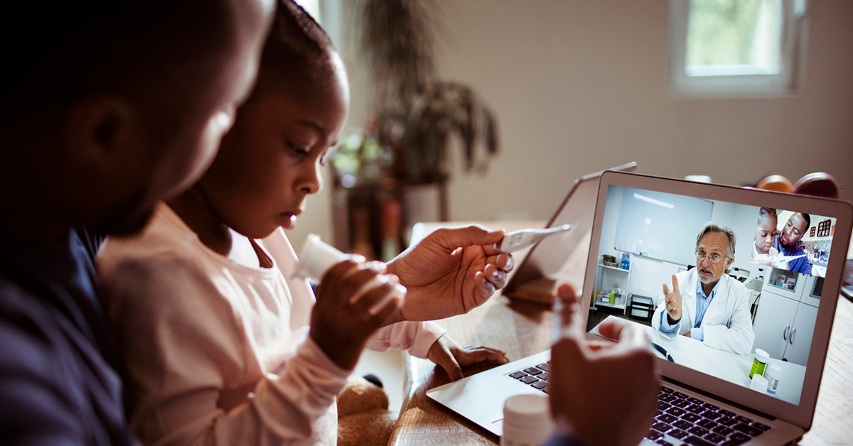 A Black father and child participate in an e-visit with a provider.