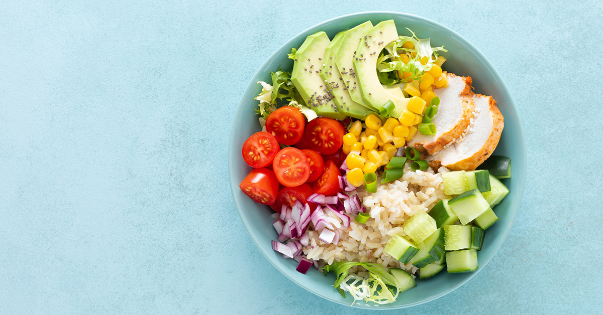 A green bowl filled with mostly vegetables and two slices of poultry.