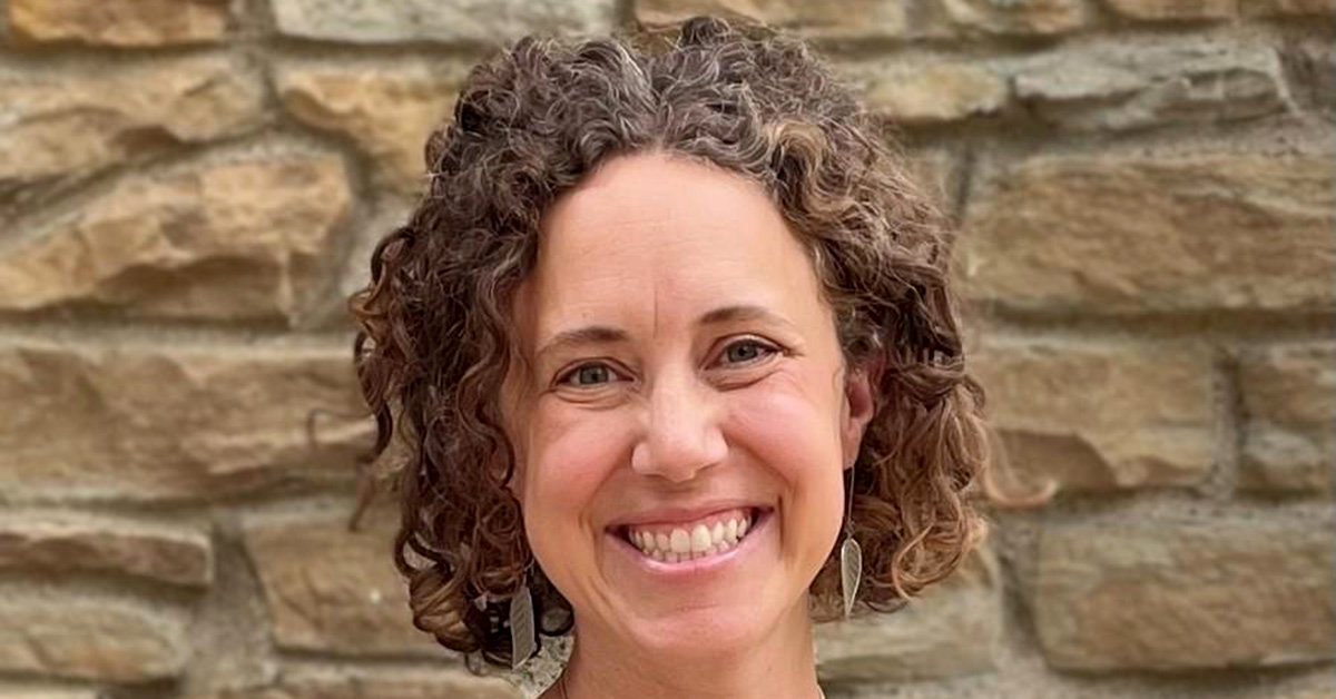 Carrie Henning-Smith smiling in front of a stone wall.