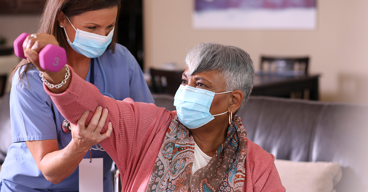 A healthcare provider helps a resident do arm exercises.