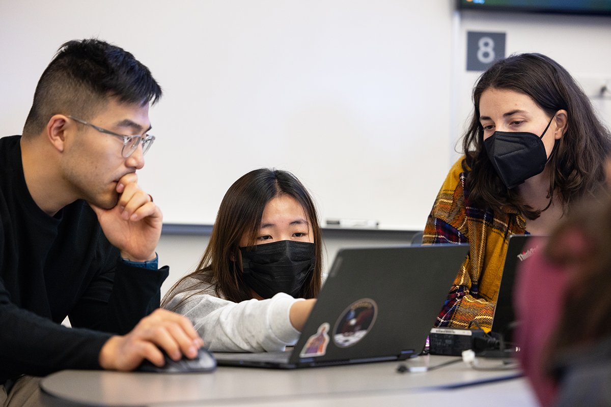 students confer over a laptop