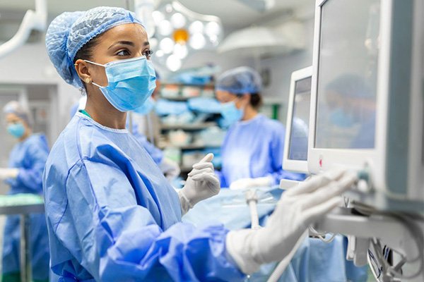medical person in full scrubs touching monitor
