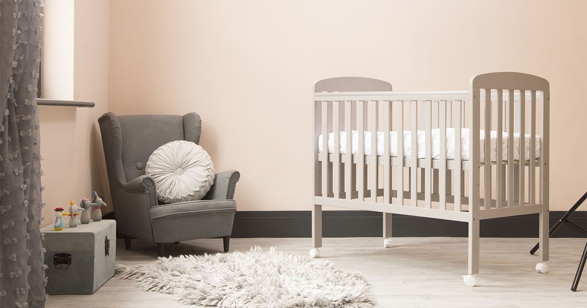 baby's room with comfortable chair and an empty crib, white rug on floor