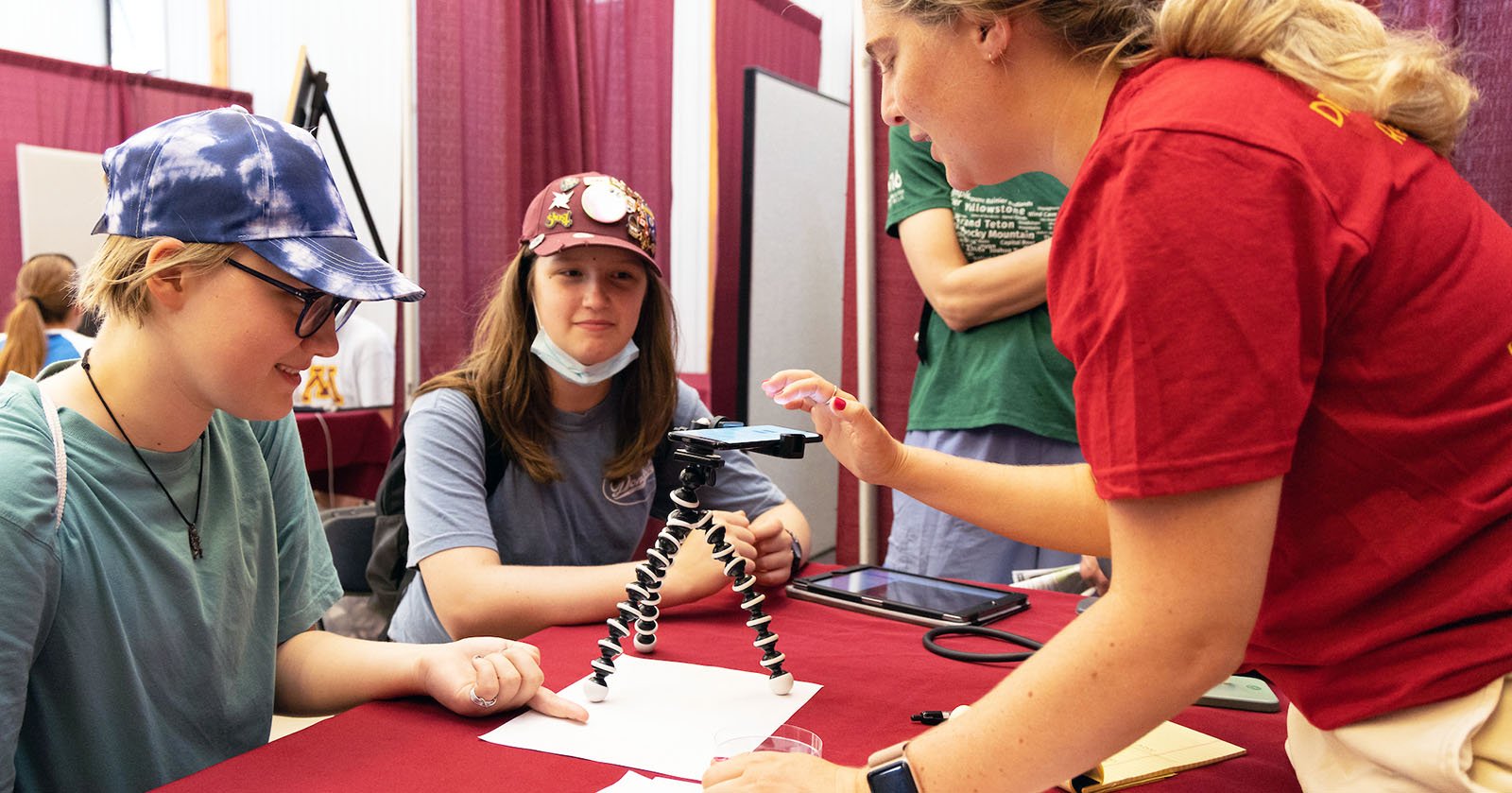 fair goers at a table looking at a phone in the D2D building