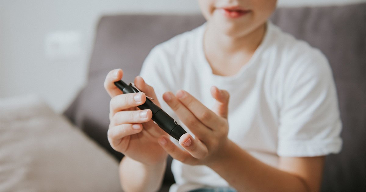 boy in white t-shirt oy measuring blood sugar level with blood glucose meter at home